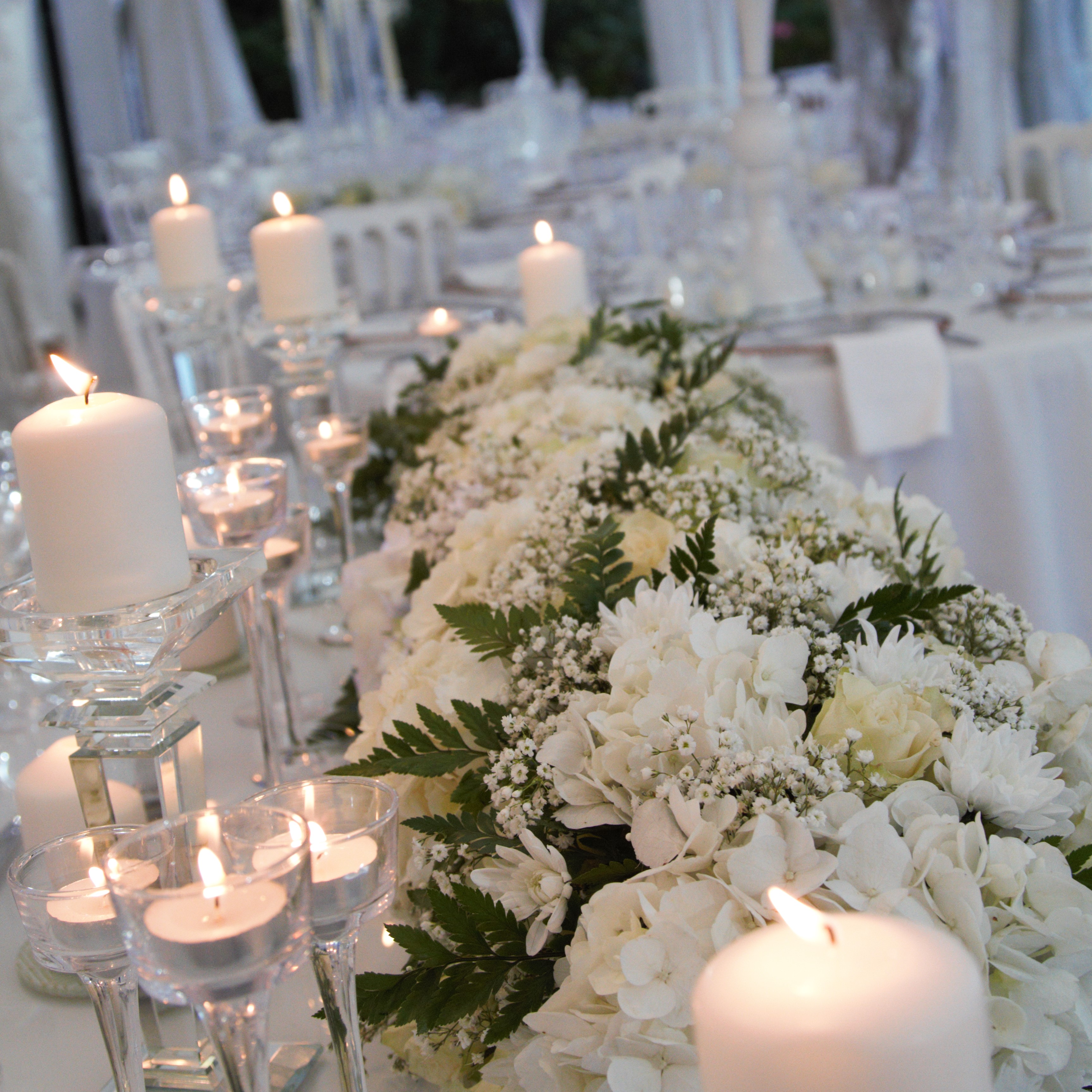 Bougies et compositions florales blanches pour table de mariage